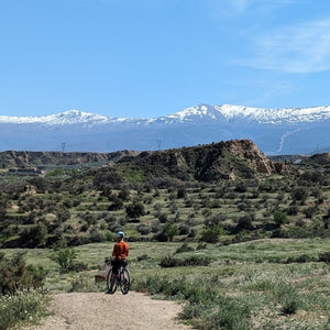 Gravel rider gazing at the snow-capped Sierra Nevada mountains, part of an off-road cycling adventure on Hidden Tracks Cycling's Flamenco Gravel trip in Spain