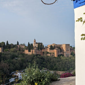 The Alhambra Palace in the background, with a gravel rider on a scenic route, showcasing the rich history and stunning landscapes of Spain during Hidden Tracks Cycling's Flamenco Gravel trip.