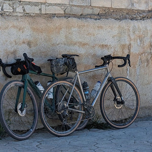 Two gravel bikes leaning against an old rustic stone wall in Andalucia, set against the backdrop of the scenic Spanish landscape during Hidden Tracks Cycling's Flamenco Gravel trip.