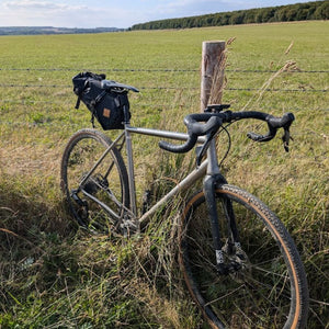 A gravel bike leaning against a wire fence , ready to set off towards Paris on Hidden Tracks Cycling's Trail of Two Cities ride between London and Paris
