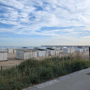 London to Paris gravel ride showcasing beach huts on a sandy beach in Calais and a scenic view from the hotel.