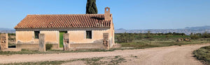 Gravel bike track passing by a lonely house in the middle of the Badlands, part of a guided bike ride in Spain on Hidden Tracks Cycling's Flamenco Gravel trip in spring