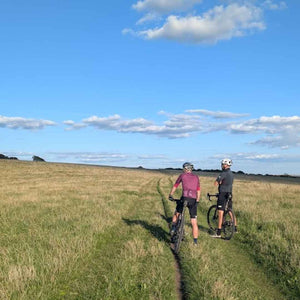 a pair of Gravel cyclists pausing to look at the view across the open grass fields of the South Downs