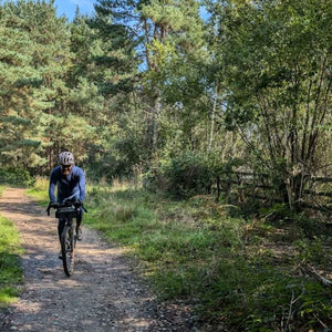 Single cyclist on a gravel path running through a wood near Crawley enroute for Brighton on Hidden Tracks Cycling's Landrace gravel bike ride from London to Brighton