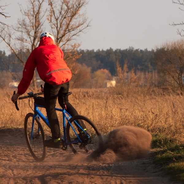 skilled gravel rider cornering at speed and kicking up a dust storm