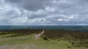 View from the top of Exmoor showing a gravel track across open moorland under heavy skies during a UK gravel ultra recce