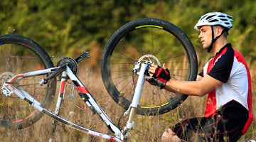 Cyclist mending a puncture in an open field 