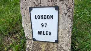 A white painted mile post depicted London 97 miles away