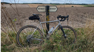 Charlie's gravel bike leaning against a Byway marker post on the Ridgeway, part of the route of Hidden Tracks Cycling's Wrecker ride 