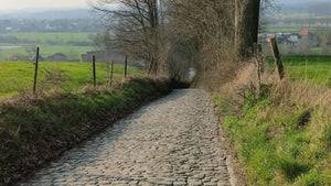 Steep cobbled lane bordered by hedgerows, classic Flanders-style terrain featured on the London to Brussels gravel cycling adventure.