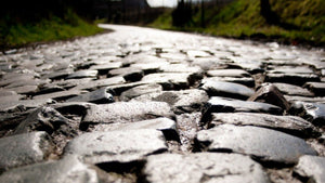 Close-up of rough cobbled road in Belgium, iconic terrain inspired by the Spring Classics on the London to Brussels gravel cycling bike adventure.