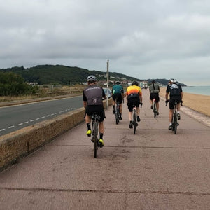 Group of Gravel cyclists riding on the concrete seafront in Hythe on a Hidden Tracks Gravel bike adventure 