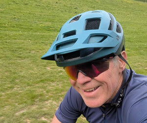 Cyclist riding off road during gravel and cyclocross coaching session in London, wearing helmet and sunglasses on grassy trail