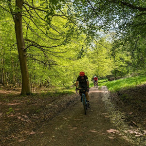 Group of Gravel riders cycling through woods on a Hidden Tracks Cycling Guided Gravel ride 