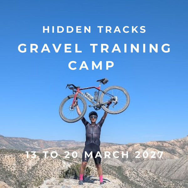 Hidden Tracks Gravel Training Camp, a cyclist holds his bike aloft on a rocky outcrop above the Gorafe Desert badlands, Andalucía
