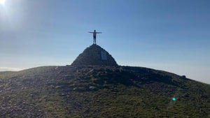 Cyclist with arms in the air atop a Cairn in the Quantock Hills 