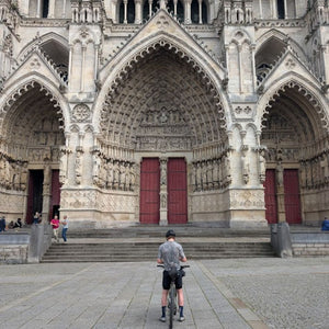 Gravel bike rider admiring the magnificent carved stone entrance to Amiens Cathedral as seen on Hidden Tracks London to Paris cycling adventure.