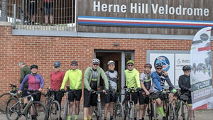Group of cyclists standing outside Herne Hill Velodrome with bicycles.