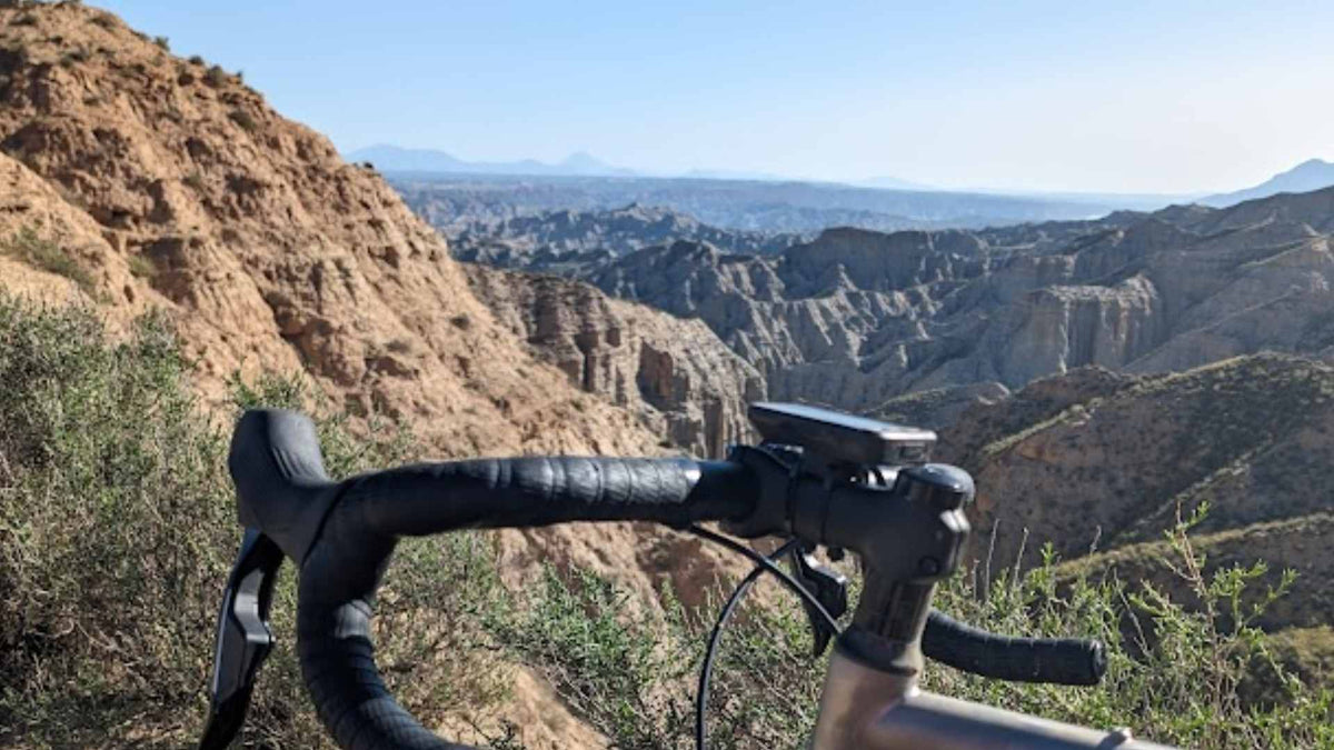 Bicycle handlebar with a scenic view of desert cliffs and mountains.