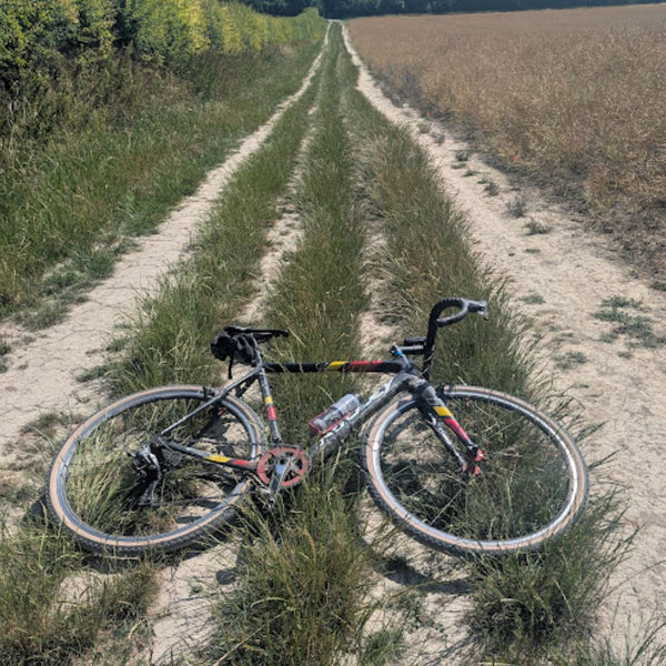 Gravel bike resting across a grassy double-track path through farmland on the Drover's Road to Winchester route.