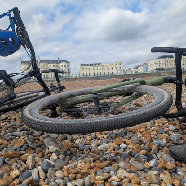 Bike resting on Brighton's pebble beach with the seafront terraces behind, at the finish of the No Hills to Brighton route.