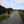 Load image into Gallery viewer, Cyclist on a flat gravel path beside wildflowers, with walkers ahead, on the No Hills to Brighton route.
