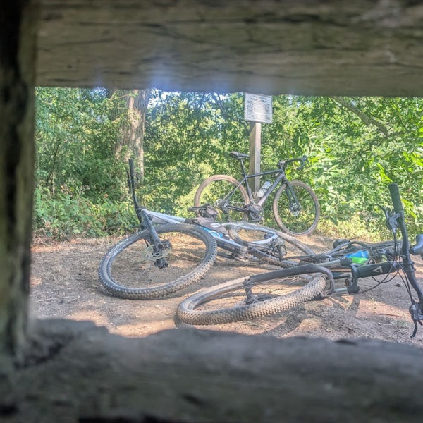 Mountain Bikes resting at a trailside WW2 pillbox, framed through its concrete gunport, on the No Hills to Brighton route.