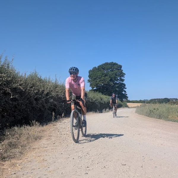 A rider on the Oxfordian GPX gravel bike route from London to Oxford, on a sunlit gravel lane through the Chiltern countryside.