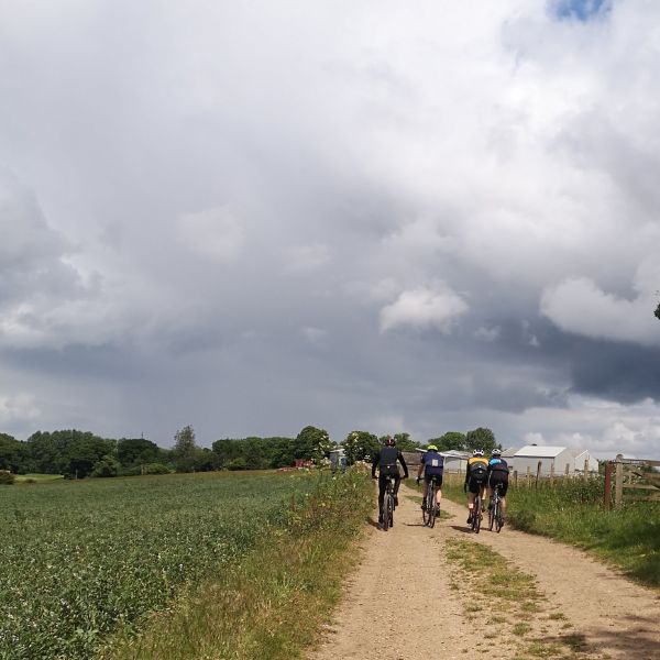 Group of 4 cyclists riding on a farm track 