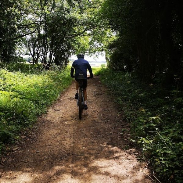 Single gravel cyclist riding on gravel bridlepaths near Epsom, Surrey on Hidden Tracks Cycling’s Roman road to Box Hill bike route.