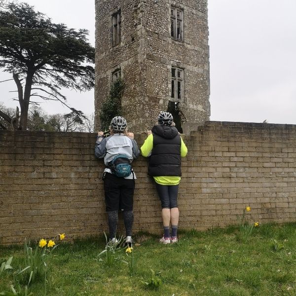 Whats over the wall- two cyclists looking t an ancient tower 