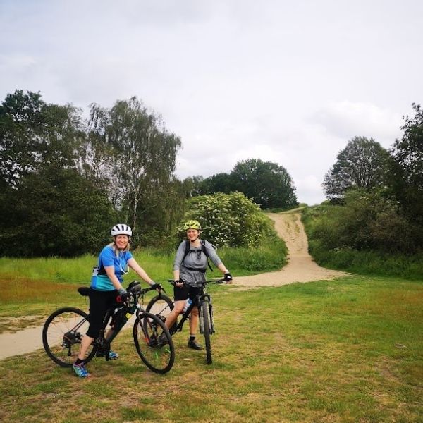 Two riders pause with their bikes on the open grassland of Mitcham Common on the Ophelia in the Hogs Mill route.